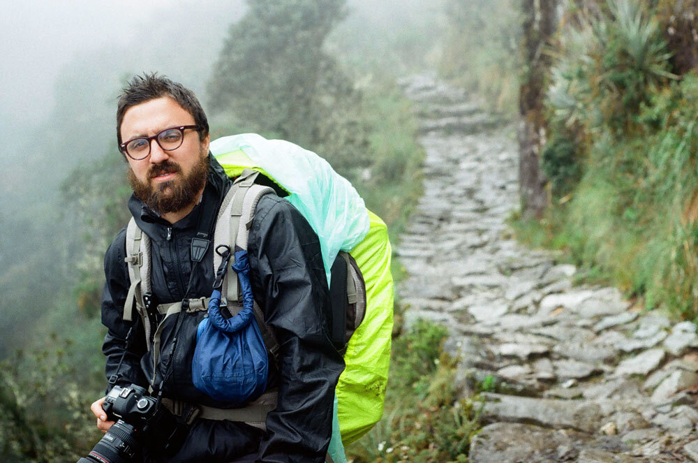 Matt on the Inca Trail in Peru in rain gear holding a camera on a misty day