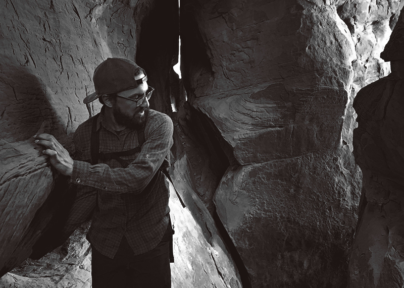 Black and white photo of Matt scrambling around a sandstone rock formation